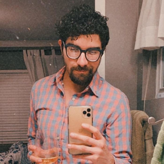 Reviewer with short, black curls capturing a mirror selfie