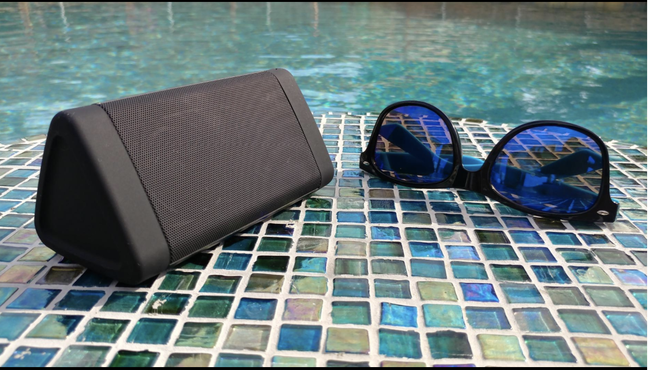 A reviewer's speaker placed on the ground next to the edge of a pool