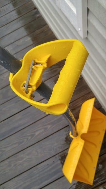 The attachment, which features a handle grip, fits onto a shovel.