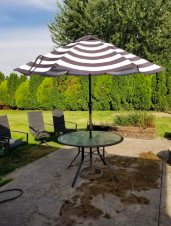 A patio scene featuring a round glass table topped with a striped umbrella