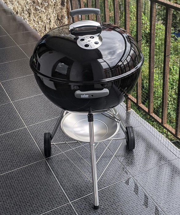 A reviewer showing off the black grill on a raised patio
