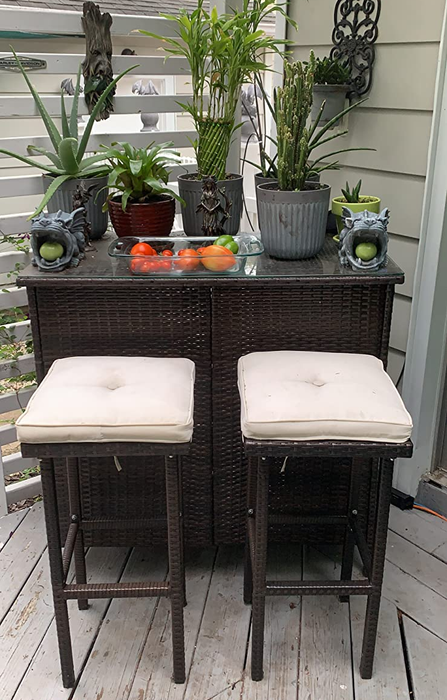 A reviewer’s photo showing the bar set with cream-colored cushions, complemented by an array of plants.