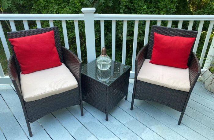 A reviewer's image showing two rattan armchairs with a matching side table topped with glass.