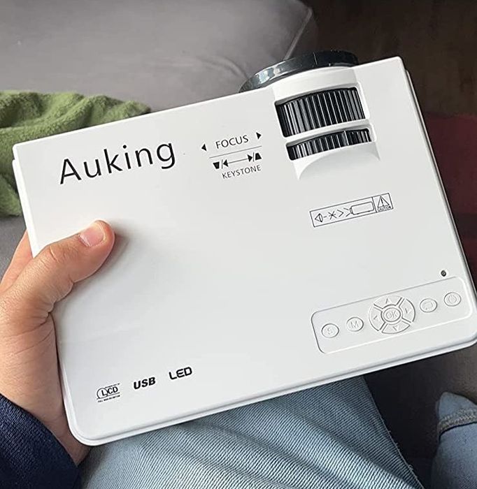 A reviewer holding the white projector to demonstrate its size