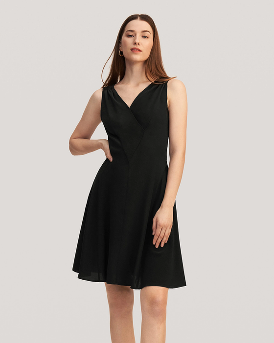 A model wearing a sleeveless black silk mini dress with a V-neckline and an A-line skirt, posed against a white background.