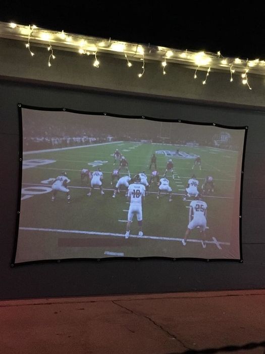 A projection screen displaying a football game