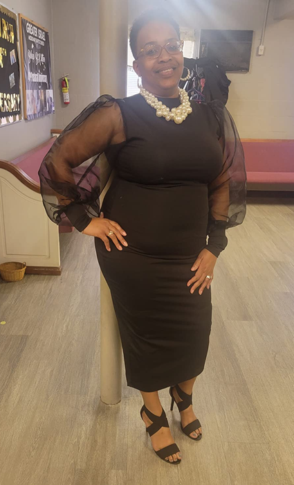A reviewer wearing the product with a chunky pearl necklace and black open-toed heels, standing on a hardwood floor.