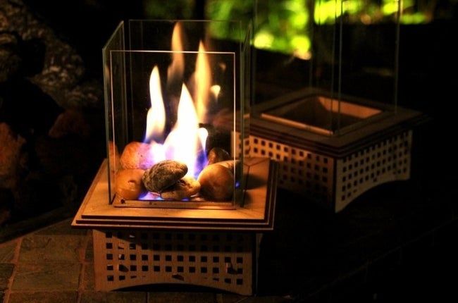 A tabletop fireplace burning on rocks and placed elegantly on a table