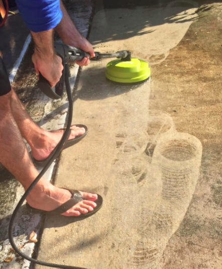 A reviewer uses a green electric pressure washer to clear grime from their driveway