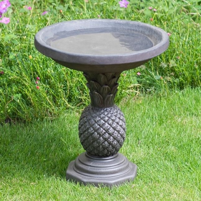 the pineapple birdbath nestled in a lush garden