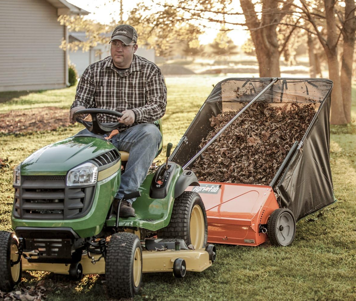 A lawn sweeper being towed behind a tractor.