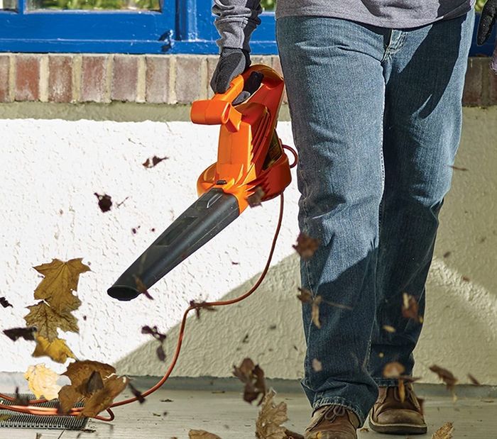 a person holding the leaf blower with a bright orange handle