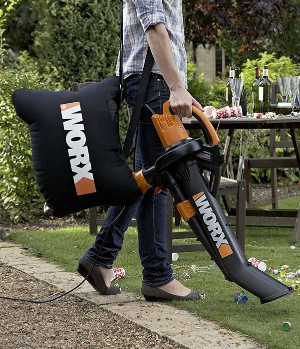 A person operating the leaf blower with the mulcher bag draped over their shoulder