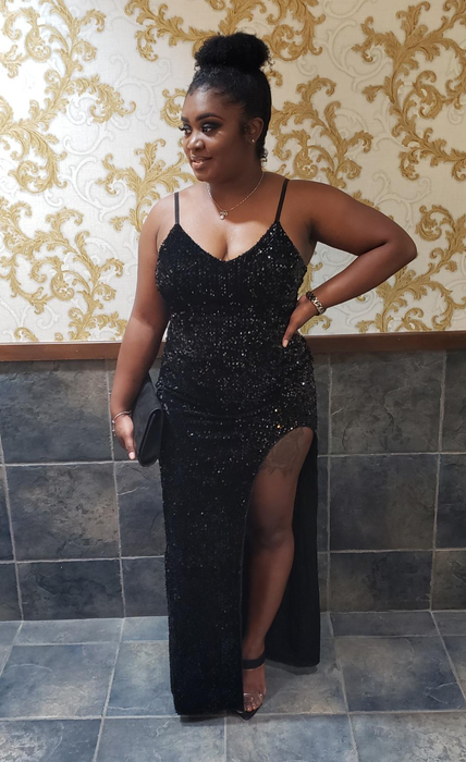 A reviewer wearing a sleeveless sparkly maxi bodycon dress with a side slit and black open-toed heels, standing on a tile floor.