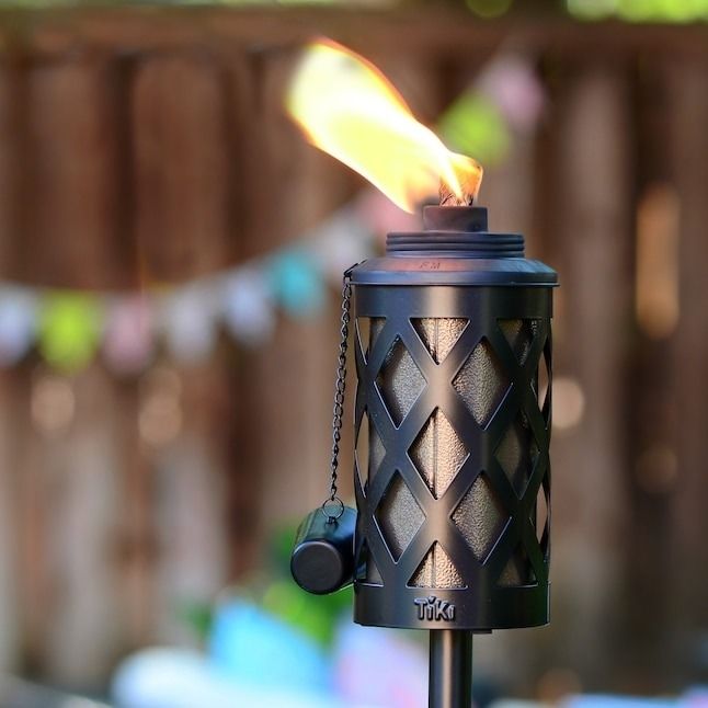 a garden torch made of steel emitting a warm flame