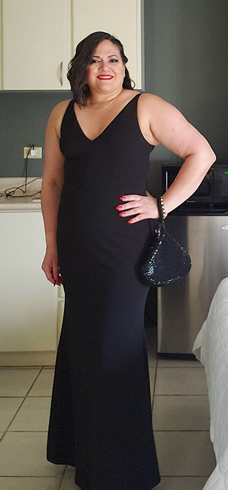 Reviewer in a sleeveless black maxi dress with a V-neckline and mermaid skirt, posing in front of white cabinets.