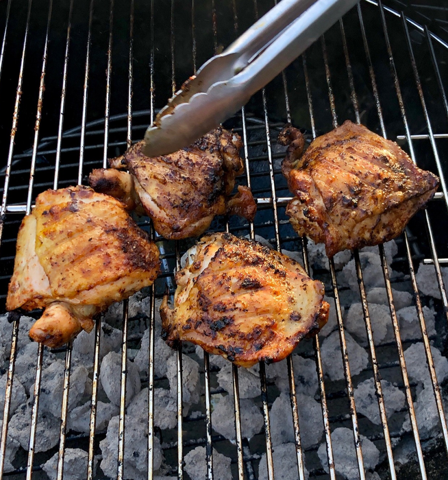 A reviewer grilling chicken on the Weber