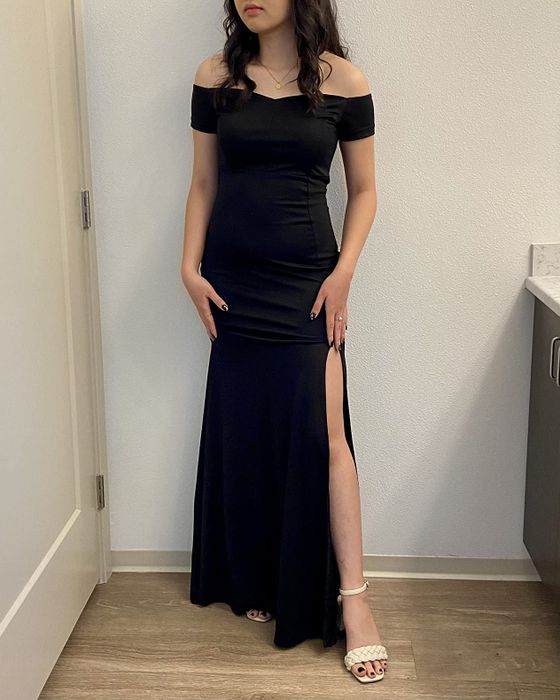 A reviewer showcasing the dress with nude braided open-toed heels, standing against a white wall.