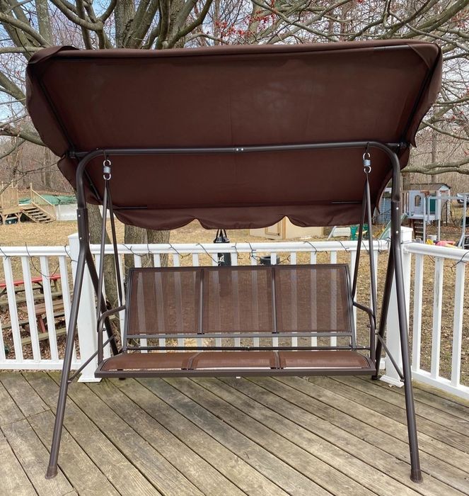 A reviewer’s photo of their brown glider swing on the porch