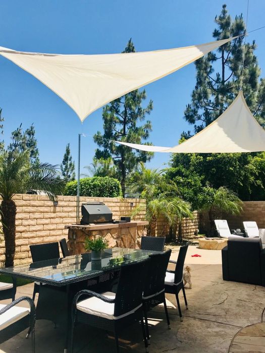 A reviewer’s backyard showcasing two beige triangular shade sails