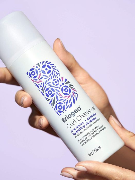 Model's hand holding the Briogeo shampoo bottle
