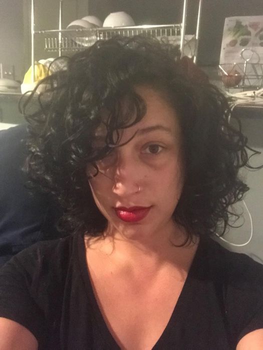 A selfie of a reviewer with voluminous black curls and bold red lipstick