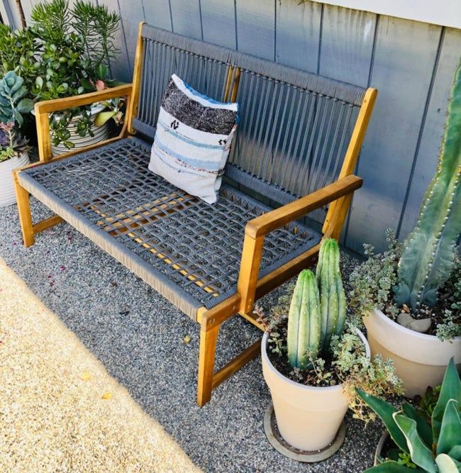 A reviewer's photo of the gray woven bench set up in their yard