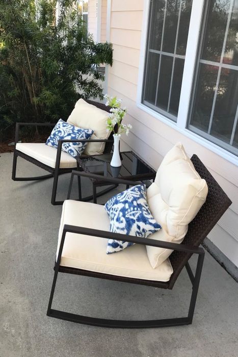 A reviewer's two rocking chairs with soft cream cushions and a matching side table placed between them