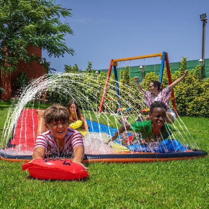 Three models joyfully sliding through a sprinkler on the slip-and-slide boards.