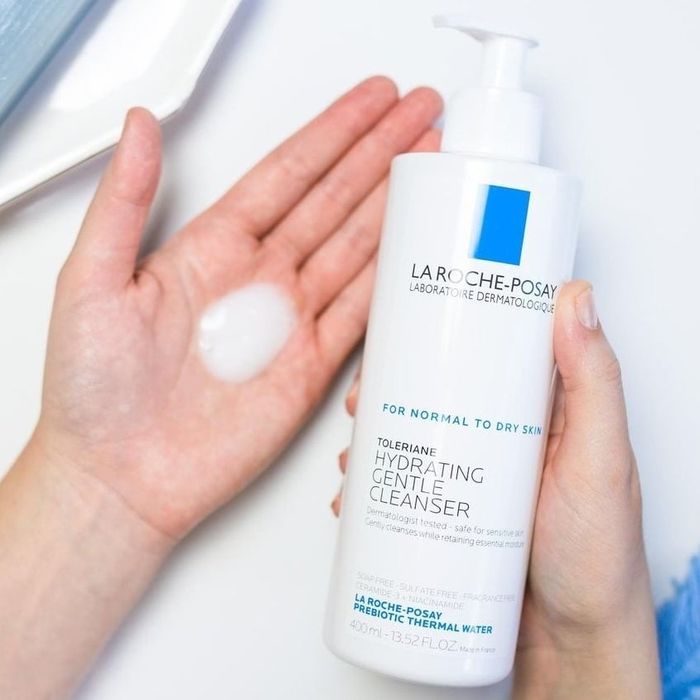 a model holding a white bottle of cleanser with a pump dispenser