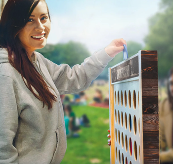 A person placing a blue disc into the massive Connect 4 game for their turn.