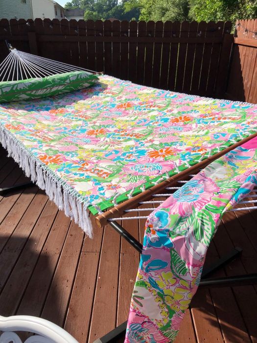 A reviewer’s colorful floral-print hammock with tassels resting on a wooden deck outdoors.