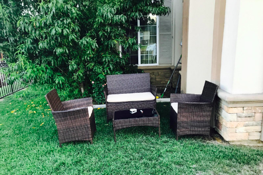 A reviewer's furniture set placed on lush green grass beside a house