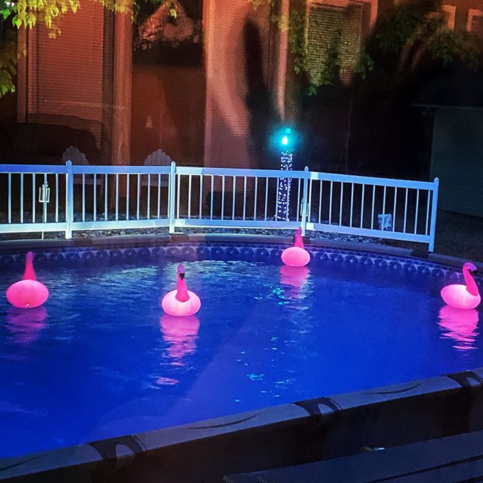 Pink flamingo-shaped floating lights illuminating the reviewer's pool at sunset.