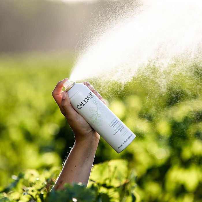 model holding a white can labeled "Caudalie"