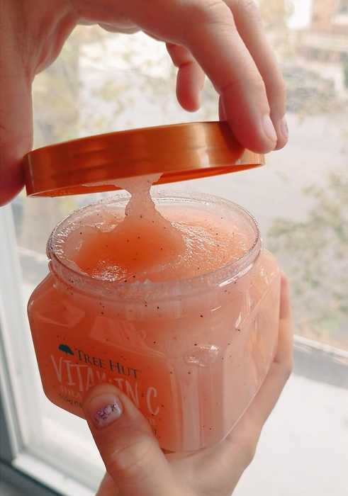 A reviewer showing off a jar of the Tree Hut Vitamin C scrub.