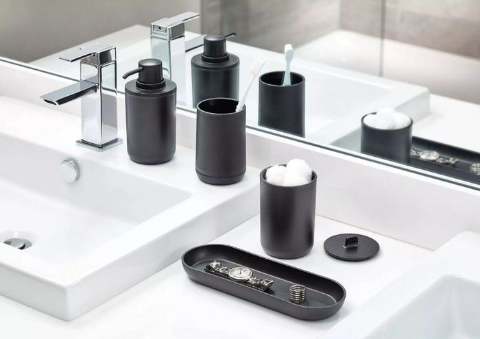 A black four-piece bathroom set featuring a bottom tray, soap dispenser, toothbrush holder, and lid canister, all neatly arranged together.