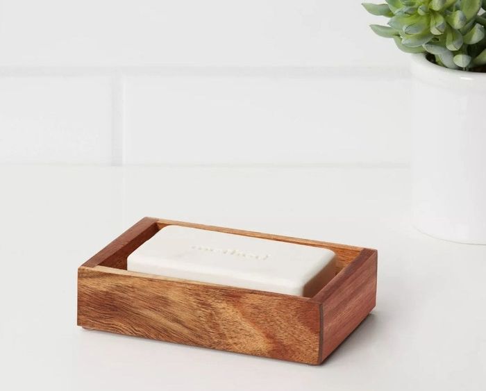 A dark wooden soap holder with a white bar of soap placed on top.