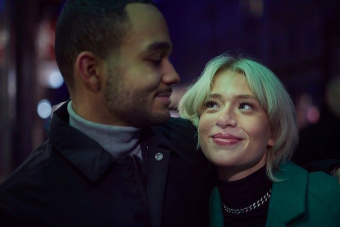 Two people exchanging warm smiles in a cozy, nighttime environment