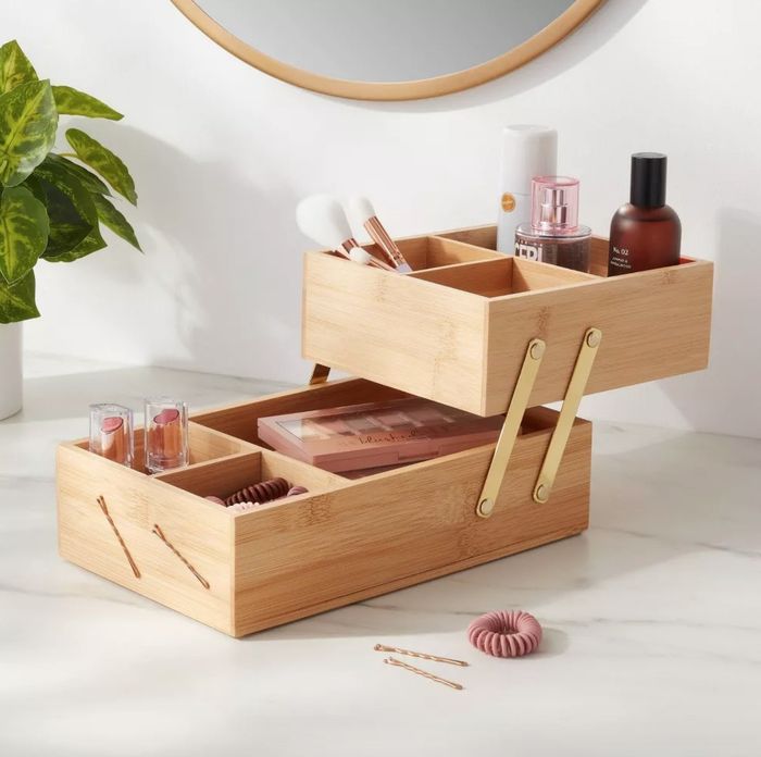 A two-tier wooden vanity organizer featuring makeup products neatly arranged within its compartments.