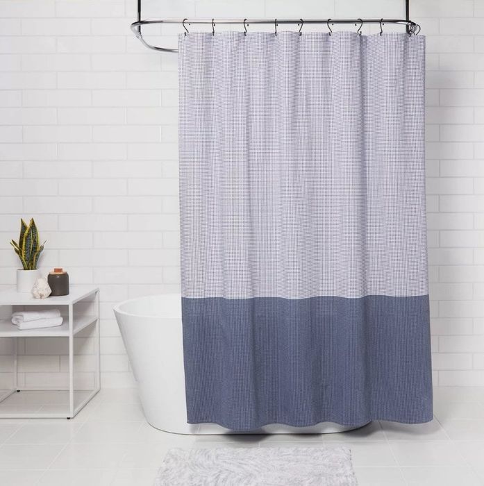 Shower hooks holding a blue shower curtain in place.