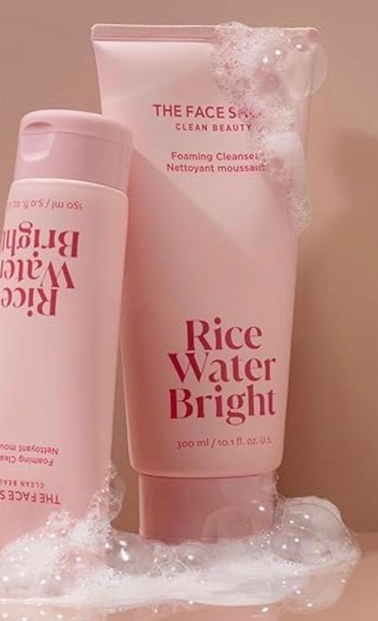 Two bottles of Rice Water Bright foaming cleanser resting on a bubbly surface