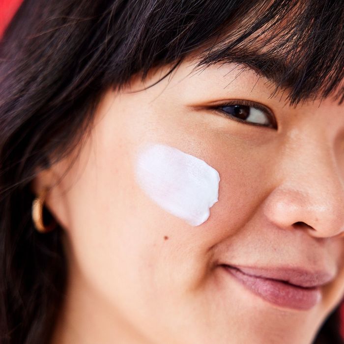 A model applying a swatch of cream to their face.