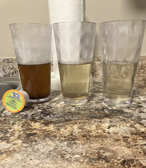 Reviewer’s photo of three glasses filled with liquids in different shades, from brown to clear, demonstrating the effectiveness of the cleaning K-Cups on their coffee maker