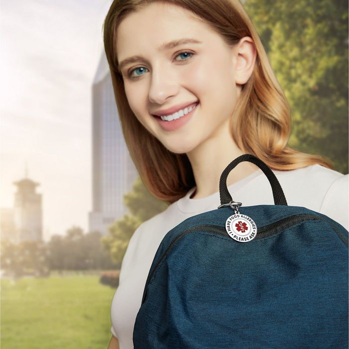 A cheerful individual holding a blue backpack with a keychain that reads 