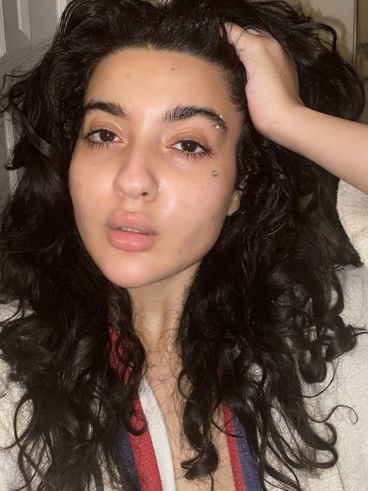 A reviewer showcasing their glowing, dewy skin after using the moisturizer.