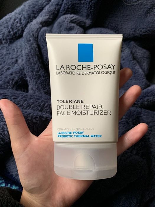 A reviewer holding the tube of the moisturizer in their hand.