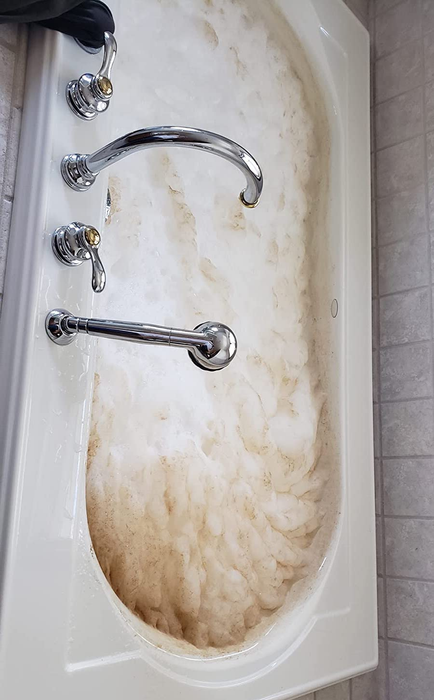 A reviewer's photo showing a tub filled with dirty foam during the cleaning process