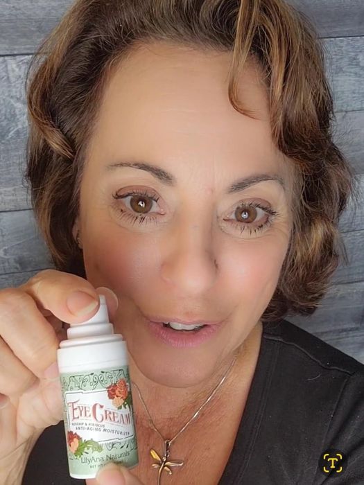 The reviewer holding the bottle of eye cream