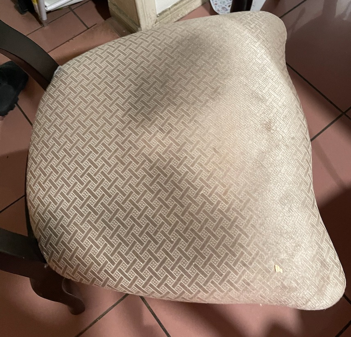 A reviewer's photo showing a dining room chair seat with visible stains before cleaning